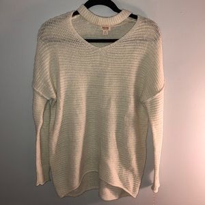 A white sweater with a cut-out neckline.